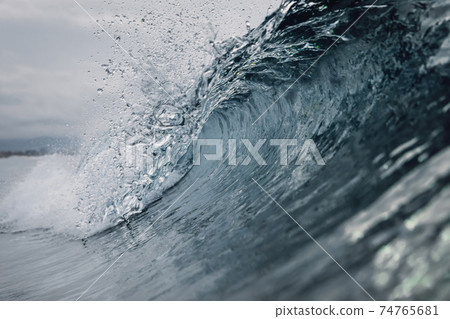 Perfect ocean waves with blue water cloudy dark sky. 74765681