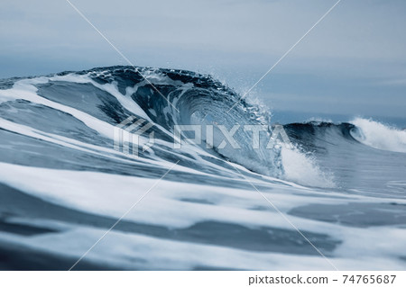 Perfect ocean waves with blue water cloudy dark sky. 74765687