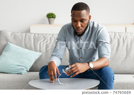 African Guy With Pulse-Oximeter Measuring Level Of Oxygen Saturation Indoor 74765689
