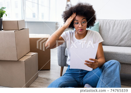 Shocked Black Lady Reading Bill Sitting Among Moving Boxes Indoor Shocked Black Lady Reading Bill Sitting Among Moving Boxes Indoor 74765839