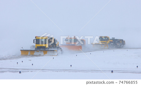 Snowy winter - three big snow removing trucks removes snow from the path on the way 74766855
