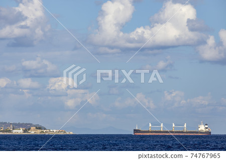 cargo ship nearby Capo Peloro Lighthouse in Punta del Faro on the Strait of Messina, most north eastern promontory of Sicily, Italy cargo ship nearby Capo Peloro Lighthouse in Punta del Faro on the Strait of Messina, most north eastern promontory of Sicily, Italy 74767965