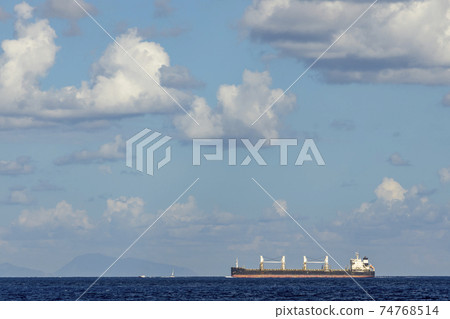 cargo ship nearby Capo Peloro Lighthouse in Punta del Faro on the Strait of Messina, most north eastern promontory of Sicily, Italy cargo ship nearby Capo Peloro Lighthouse in Punta del Faro on the Strait of Messina, most north eastern promontory of Sicily, Italy 74768514