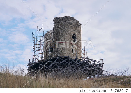 ruins of medieval fortress tower in the scaffolding during reconstruction 74768947
