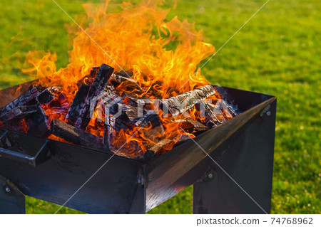 The concept of a picnic. Fire during a picnic on a green lawn for a picnic with a blurred background. 74768962