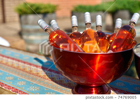 Bottles of pink wine in a bucket of ice on the table. Bottles of pink wine in a bucket of ice on the table. 74769005