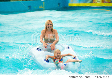 a woman with a child in a rubber inflatable circle plays in the pool of a summer water park in the rain a woman with a child in a rubber inflatable circle plays in the pool of a summer water park in the rain 74769643