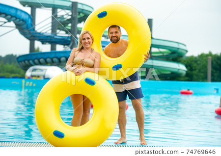 a man and a woman in a rubber inflatable circle stand against the background of a summer water park pool a man and a woman in a rubber inflatable circle stand against the background of a summer water park pool 74769646