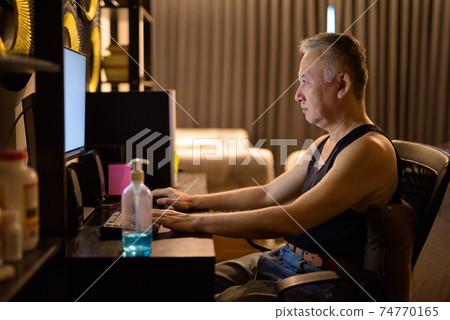 Portrait of mature Japanese man using computer at home 74770165