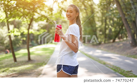 Woman drink water red bottle after morning workout. Woman drink water red bottle after morning workout. 74770247