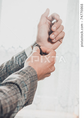Groom's morning, details and husband's meeting on the wedding day. Man adjusts a watch on his hand on a white background. 74770868