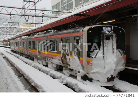 Joetsu Line E129 system stopping at Echigo Yuzawa Station in winter 74771841