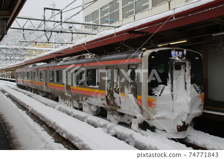 Joetsu Line E129 system stopping at Echigo Yuzawa Station in winter 74771843