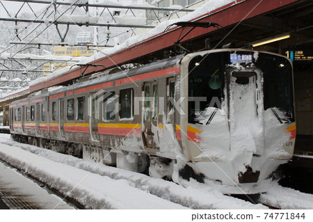 Joetsu Line E129 system stopping at Echigo Yuzawa Station in winter 74771844