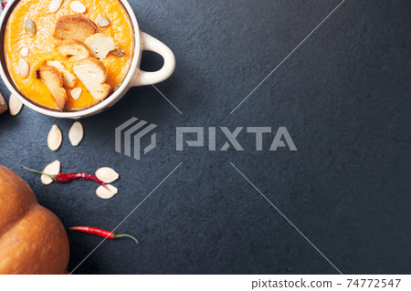 pumpkin cream soup with croutons on a black table with spices pumpkin cream soup with croutons on a black table with spices 74772547