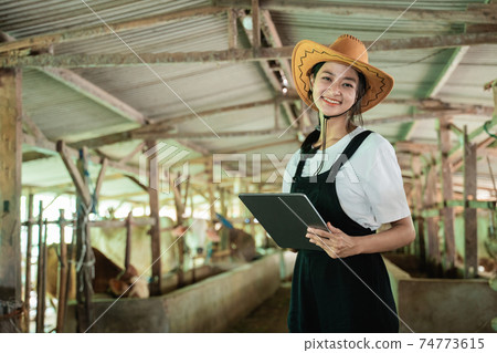 close-up of a smiling woman wearing a cowboy hat looking at the camera while touching a screen of a digital tablet close-up of a smiling woman wearing a cowboy hat looking at the camera while touching a screen of a digital tablet 74773615