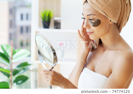 Young woman with beautiful skin puts black patches on her face 74774120