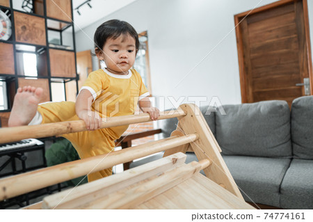 baby trying to raise its legs while climbing on the triangle toy pikler baby trying to raise its legs while climbing on the triangle toy pikler 74774161