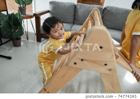 little kids climb on the pikler triangle toy while playing together little kids climb on the pikler triangle toy while playing together 74774165