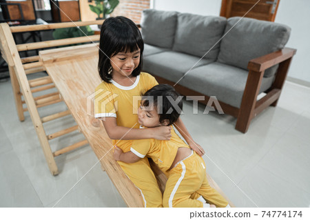 siblings patiently keep playing the slide on the pikler triangle toy together siblings patiently keep playing the slide on the pikler triangle toy together 74774174