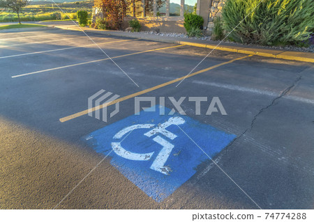 Handicapped parking space at a parking lot outside a building on a sunny day 74774288