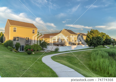 Pathway on lush green grassy ground in front of houses with balconies and stairs 74774308