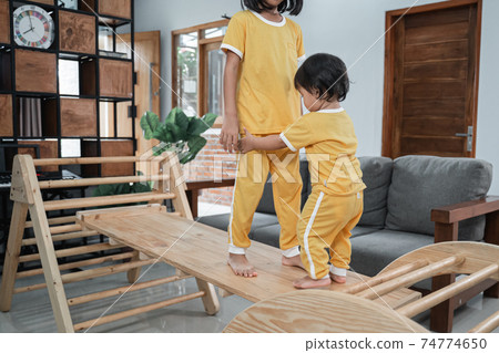 Little Baby holds its sister's feet while playing in the Pikler Triangle Toys Little Baby holds its sister's feet while playing in the Pikler Triangle Toys 74774650