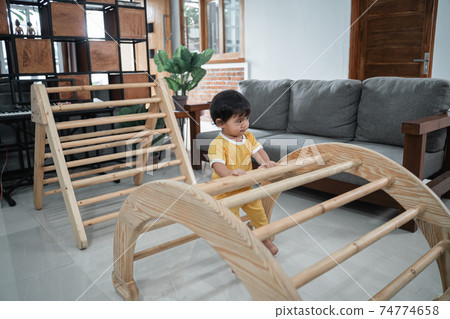 Little baby girl sitting on pikler climbing toys Little baby girl sitting on pikler climbing toys 74774658