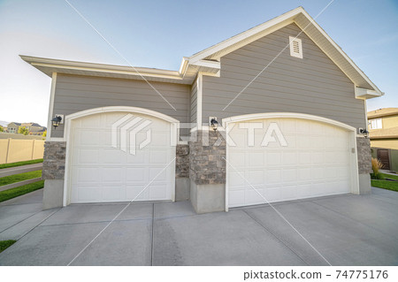 Double garages with closed doors on a sunny day 74775176