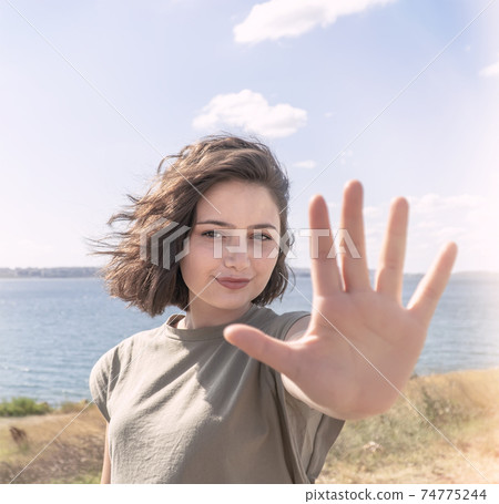 Beautiful happy young woman making stop sign with her hand. Beautiful happy young woman making stop sign with her hand. 74775244