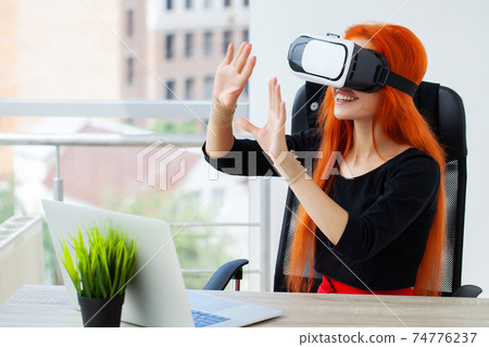 Young woman wearing virtual reality goggles in modern coworking studio. Young woman wearing virtual reality goggles in modern coworking studio. 74776237