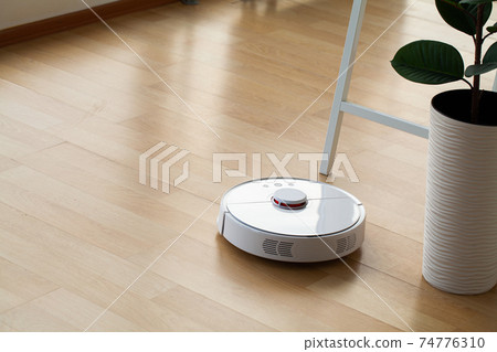 Smart House. Vacuum cleaner robot runs on wood floor in a office 74776310