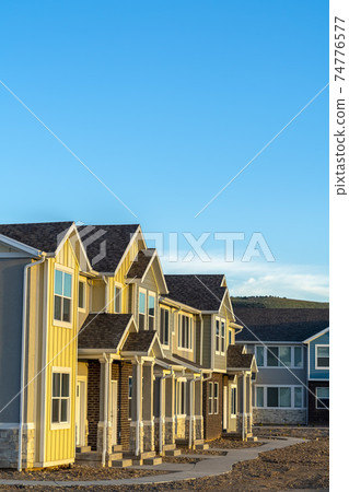 Townhomes with wood and brick exterior wall against mountain and blue sky Townhomes with wood and brick exterior wall against mountain and blue sky 74776577