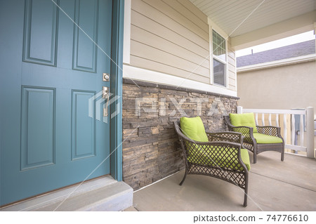 Porch armchairs against brick wall of a home with blue front door 74776610