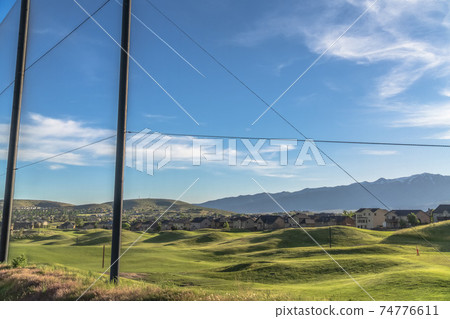 Fence with scenic view of golf course houses and mountain on a sunny day 74776611