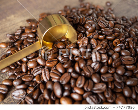 Coffee beans and golden measuring spoon 74777086