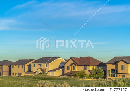 Exterior of houses with gable and valley and hip roof designs against blue sky Exterior of houses with gable and valley and hip roof designs against blue sky 74777157