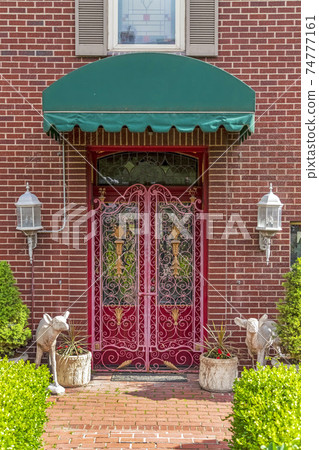 Green awning over a beautiful red door with decorative wrought iron gate Green awning over a beautiful red door with decorative wrought iron gate 74777161