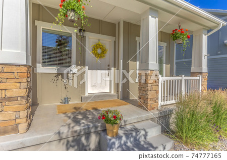 Outdoor stairs porch and white front door with wreath at the facade of a home 74777165