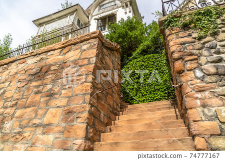 Stone staircase and stone wall with a white house and bright sky background Stone staircase and stone wall with a white house and bright sky background 74777167