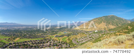 Landscape view of Salt Lake City Utah suburbs against mountain and blue sky 74778492