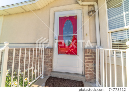 Exterior of a home with decorative oval glass paned vibrant red front door Exterior of a home with decorative oval glass paned vibrant red front door 74778512