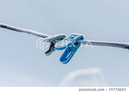 Colorful clothespins on clothesline covered with snow outdoors. Winter scene Colorful clothespins on clothesline covered with snow outdoors. Winter scene 74778603