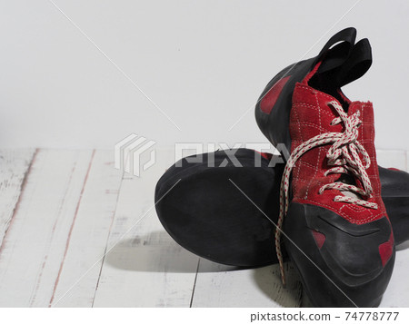 Red laced bouldering shoes on a white floor 74778777