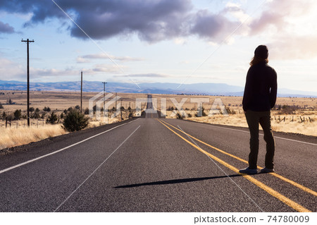 Man is standing in the middle of the long road. Man is standing in the middle of the long road. 74780009
