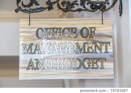 Office Of Management And Budget sign hanging on decrative wrought iron hanger 74781067