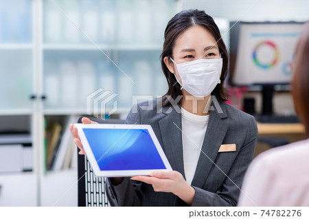 A woman wearing a mask to serve customers 74782276