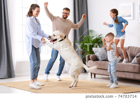Cheerful family with kids and dog dancing at home 74783714