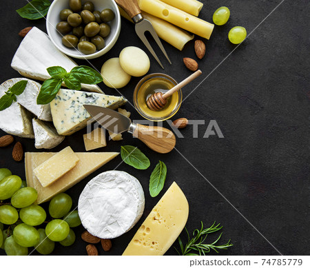 Various types of cheese, grapes, honey and snacks 74785779