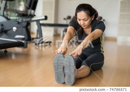 woman stretching arms to foot in fitness gym woman stretching arms to foot in fitness gym 74786871